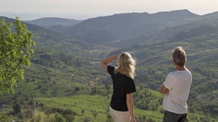 Couple pause hiking to admire landscape below
