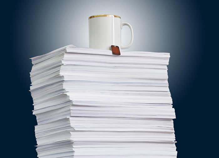 high paper stack and a cup of tea