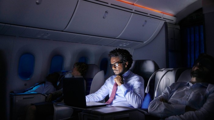 Businessman working at laptop on night airplane
