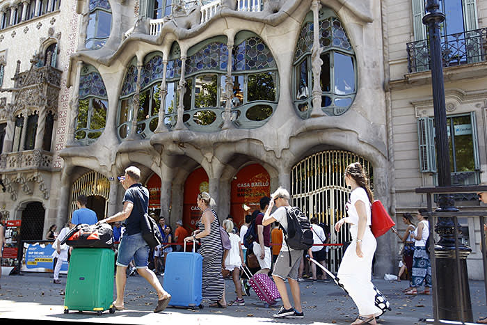 Tourists pull their suitcases in front of Spanish architect Gaudi's Casa Batllo in Barcelona on June 28, 2015