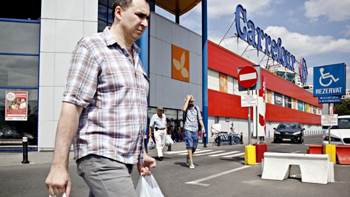 Men walk out of a Carrefour store after shopping, on July 9, 2013, in Bucharest, Romania. With 119 stores and sales of local one billion euros in 2011, the retail giant Carrefour intends to use the discovery by Romanians &quot;joys&quot; of consumption, after decades of deprivation under the communist regime. AFP PHOTO / ANDREI PUNGOVSCHI (Photo credit should read ANDREI PUNGOVSCHI/AFP/Getty Images)