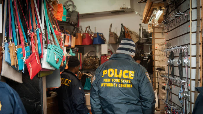 Power of enforcement: police officers removing counterfeit goods from a shop in New York