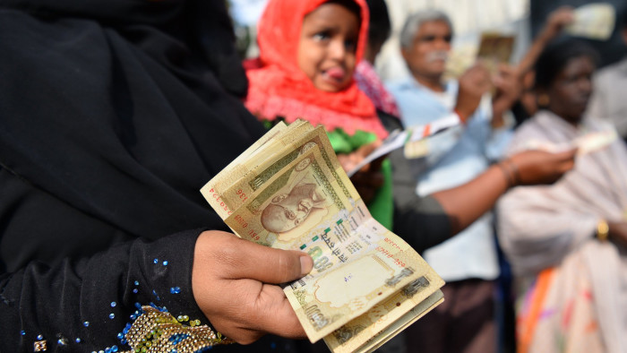 People waiting to exchange demonitised Indian currency, show their old 500 and 1000 Rupee notes near the closed gates of Reserve Bank of India in Bangalore on January 2, 2017 after acceptence of the banned notes at banks and RBI ended two days ago. / AFP / Manjunath KIRAN        (Photo credit should read MANJUNATH KIRAN/AFP/Getty Images)