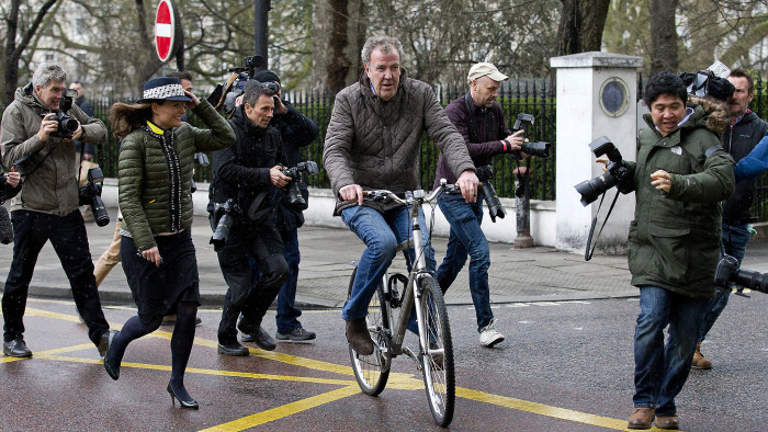 British television presenter Jeremy Clarkson (centre) leaves his home on a bicycle in west London on March 26, 2015