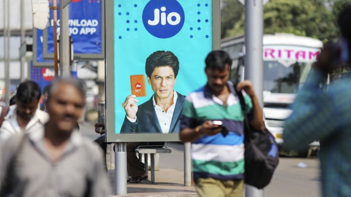 An advertisement featuring Bollywood actor Shah Rukh Khan for Reliance Jio, the mobile network of Reliance Industries Ltd., is displayed at a bus stop in Mumbai, India, on Monday, Oct. 24, 2016. Mukesh Ambani's Reliance Industries began offering mobile services last month under the Jio brand. Photographer: Dhiraj Singh/Bloomberg