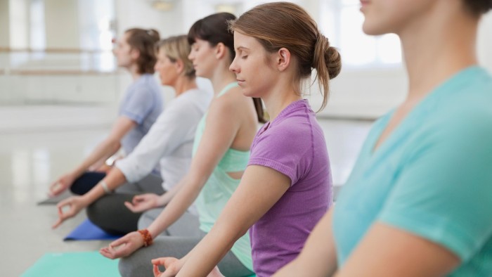 D8KNX5 Group of people practicing lotus position in yoga studio