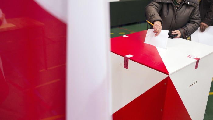 A voter casts his ballot in a ballot box during the Polish general election in Warsaw, Poland, on Sunday, Oct. 25, 2015. Poland's opposition is on the cusp of ending an eight-year rule by Civic Platform with a win in a parliamentary election on Sunday, securing a mandate to take charge of the European Union's biggest eastern economy. Photographer: Bartek Sadowski/Bloomberg