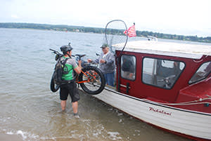 Kidd hands his bike over to Chuck Holloway for a boat ride back to Coos Bay