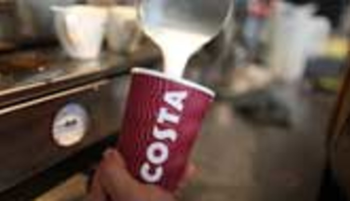 An employee pours milk during the making of a coffee at a Costa Coffee shop in London.