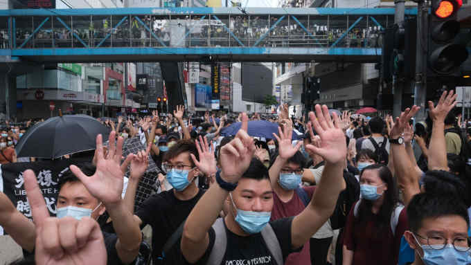 Demonstrators gesture the "Five demands, not one less" protest motto during a protest in Hong Kong, China, on Wednesday, July 1, 2020. Hong Kong woke up to a new reality on Wednesday, after China began enforcing a sweeping security law that could reshape the financial hub’s character 23 years after it took control of the former British colony. Photographer: Roy Liu/Bloomberg