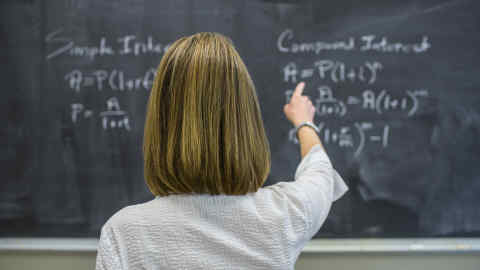 Caucasian teacher pointing to chalkboard