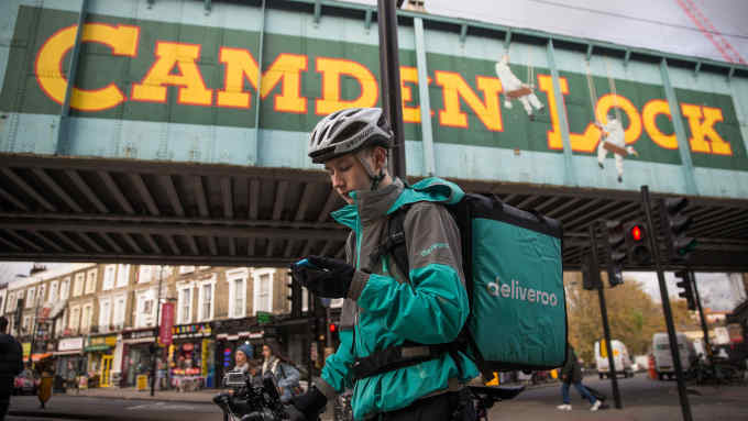 Restaurant Food Delivery company 'Deliveroo' employee, Billy Shannon looks for an address while working in Camden Town, north London in November 17, 2016. Lunch hour has just started in the north London borough of Camden, which means it's crunch time for Billy Shannon, a fresh-faced food-delivery courier. Dressed in thermal clothing to ward off the autumnal cold, the 18-year-old jumps on his bike as an order comes in, mindful that he is paid not by the hour, but by the number of deliveries he makes. / AFP / DANIEL LEAL-OLIVAS / TO GO WITH AFP STORY BY ALICE TIDEY (Photo credit should read DANIEL LEAL-OLIVAS/AFP/Getty Images)