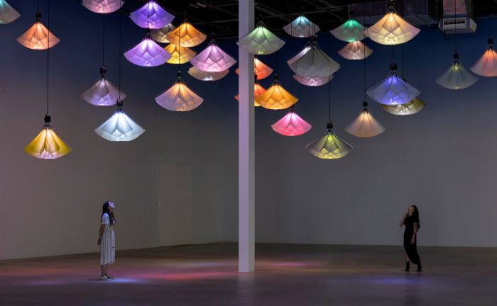 Lampshades glowing different colours hang in a dark room