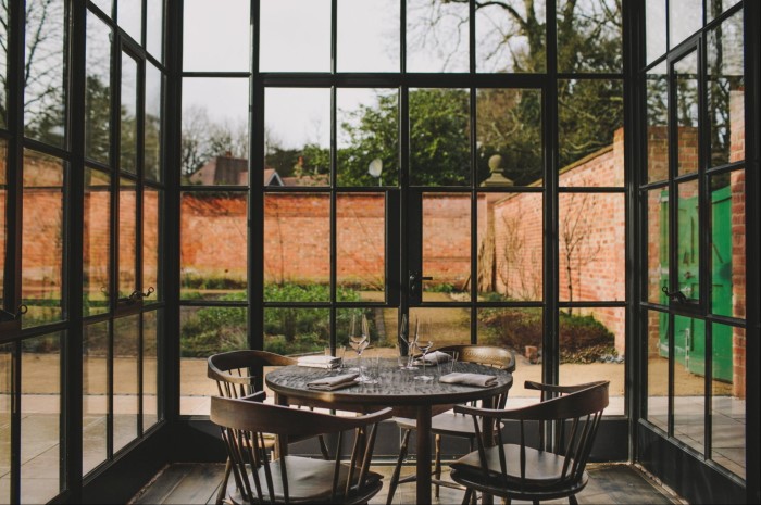 A table surrounded by floor-to-ceiling windows looking onto the walled garden at Grace & Savour