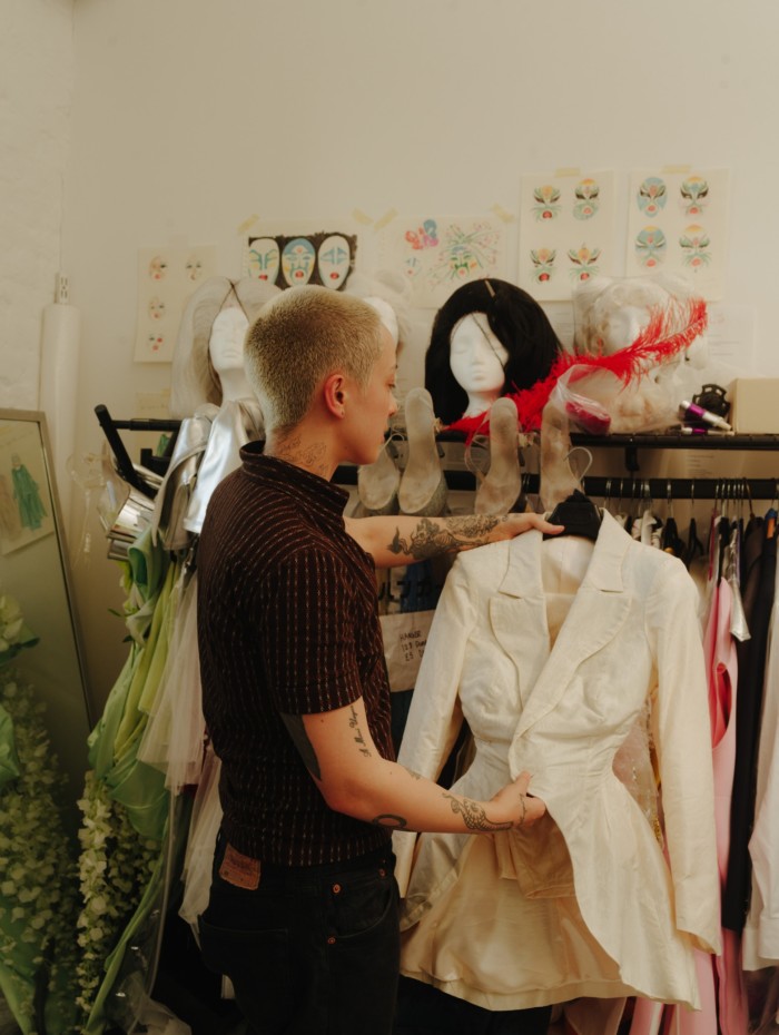 A person examine a white frock coat off a rack