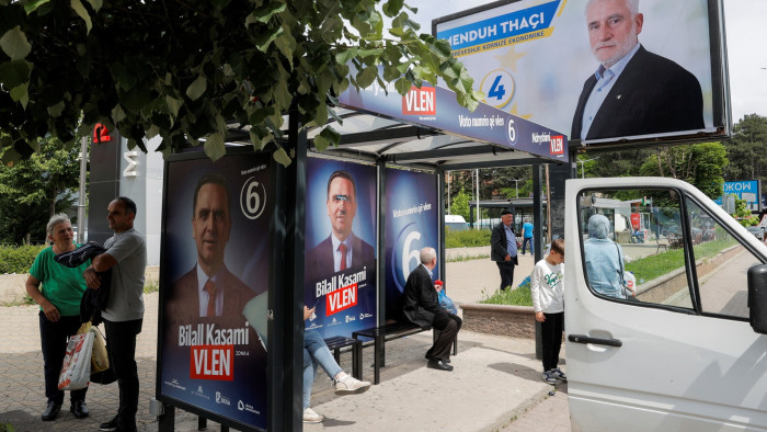 People wait at a bus station covered with campaign billboards for the upcoming parliamentary and presidential elections in Tetovo, North Macedonia May 7, 2024. 