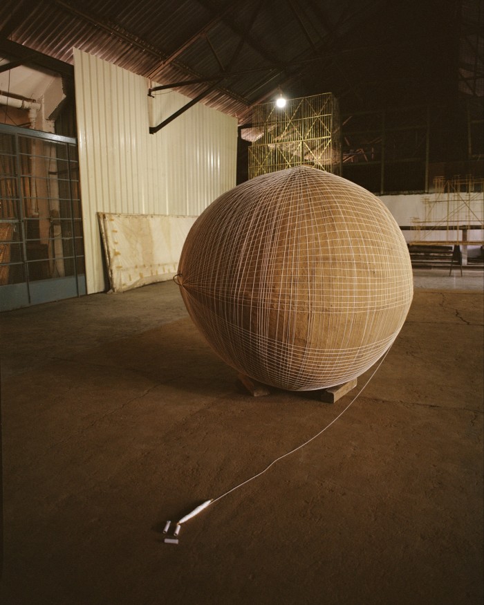 A spherical bamboo work in progress, plastered with cow dung, string and turmeric