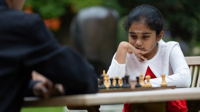 A studios-looking eight-year-old  girl at the chessboard