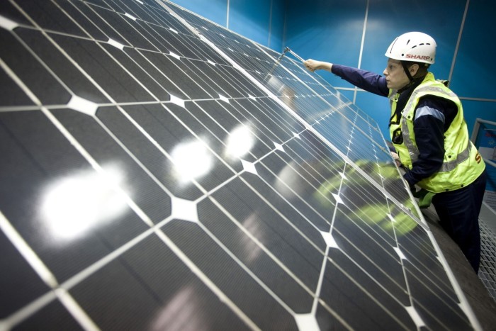 An installation trainee secures a solar panel in to position at Sharp Corp.’s solar panel production factory