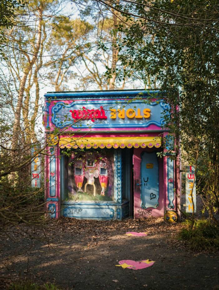 A brightly coloured toy shop frontage in a slight state of disrepair, sitting in the woods