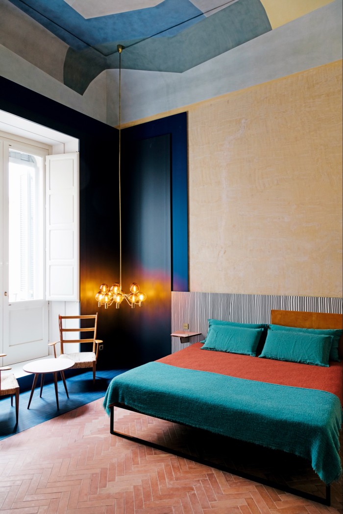 A bedroom with a 1960s ceiling lamp by Hans-Agne Jakobsson, a 1957 Gio Ponti table and 1930s chairs by Italian architect/designer Pier Giulio Magistretti