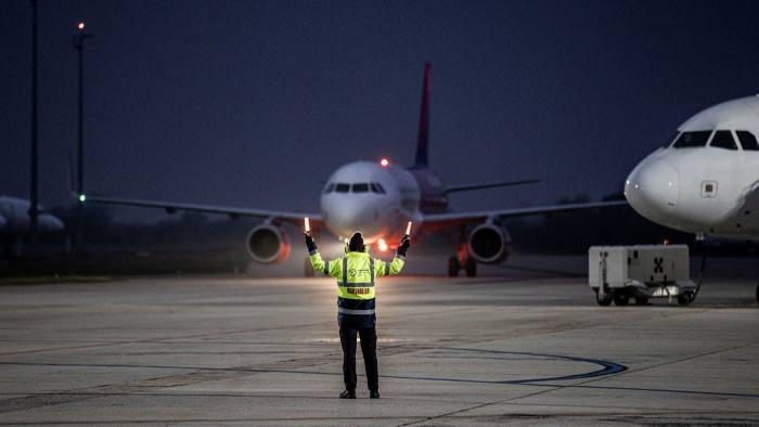 A member of ground crew directs a Wizz Air Holdings Plc passenger aircraft to the gate at Debrecen International Airport in Debrecen, Hungary