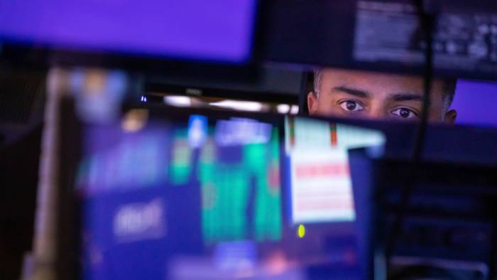 A stock trader looks at monitors