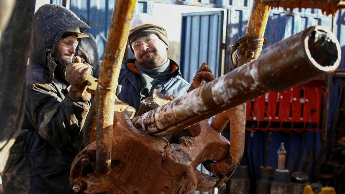 Russian oil workers raise a drill pipe onto a drilling rig