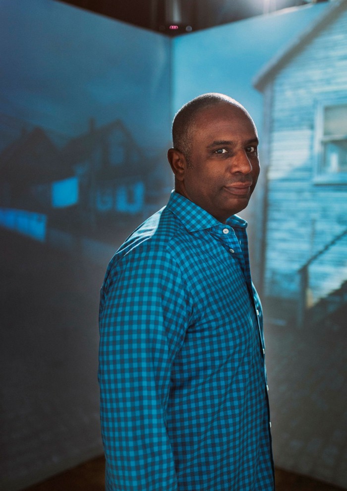 A man in a blue check shirt turning to look at the camera