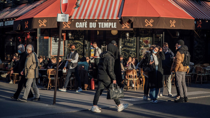 Pedestrians pass a bar in Paris, France
