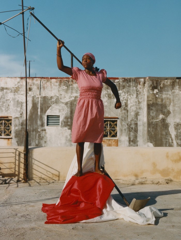 Photo of a woman in a red dress holding a long stick like a javelin