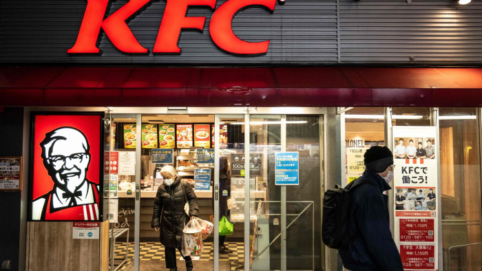 A woman holding Christmas meal boxes leaves a KFC restaurant in Tokyo
