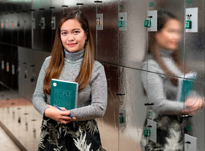 Krystelle Bolivar holds a green notebook as she stands in front of lockers