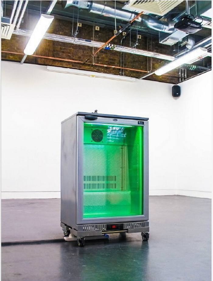 A small fridge with glass door glowing green