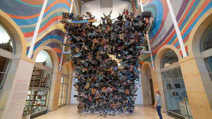 A tidal wave of black and painted wooden fragments is about to break over the viewer in a large atrium