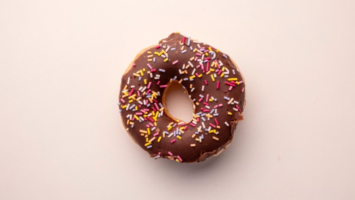 A ring doughnut covered in chocolate and multicoloured sprinkles 