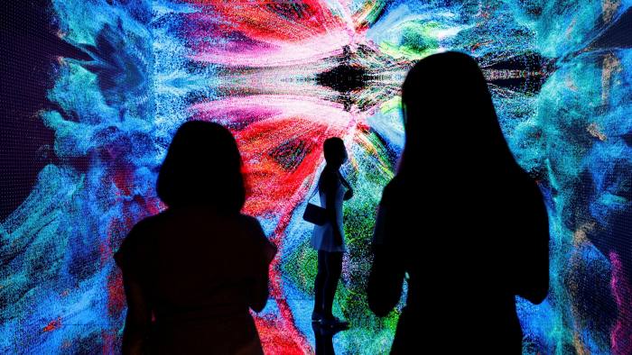 Visitors are pictured in front of an immersive art installation titled ‘Machine Hallucinations - Space: Metaverse’ 