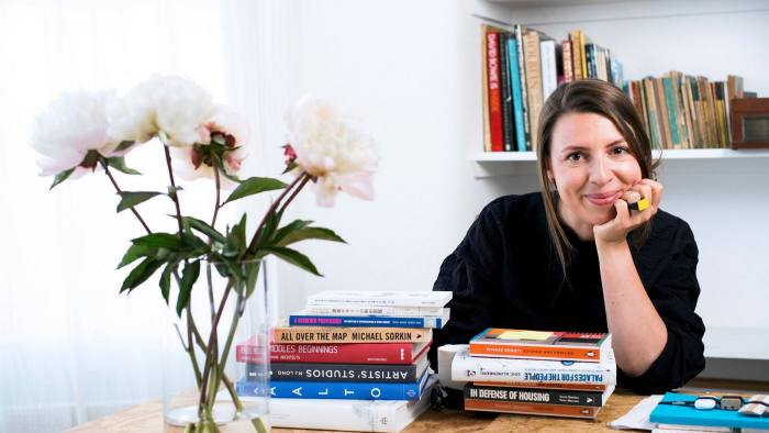 British architect, Zoe Berman, sits at a table with books and flowers