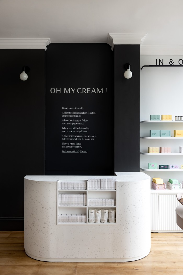 A white desk in front of a black wall at the London outpost of French beauty store Oh My Cream