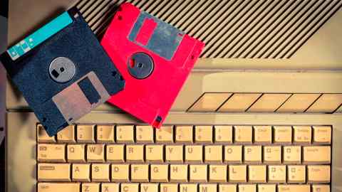 Two floppy disks placed on top of an old keyboard