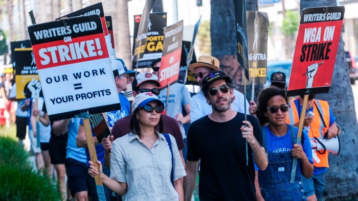 Striking writers and actors walk with pickets outside Sunset Bronson studios in Los Angeles