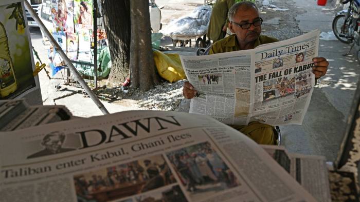 A man reads a newspaper displaying front page news about Afghanistan, at a stall in Islamabad, Pakistan
