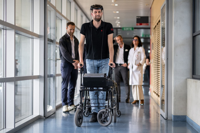 Gert-Jan Oskam uses a walker to walk down a hospital corridor