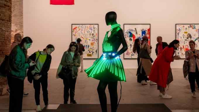 A female-form mannequin in an art gallery wearing a short skirt covered in illuminated bright green lights