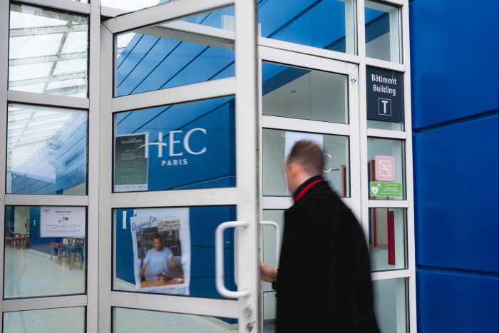 A man walks through a door with a HEC Paris sign on it