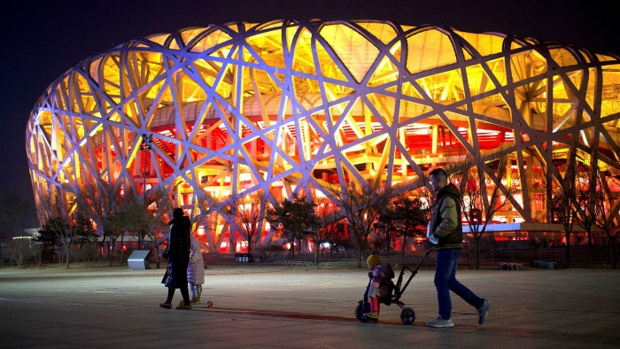 People walk past the Birds Nest stadium, the venue for the 2022 Winter Olympics, in Beijing