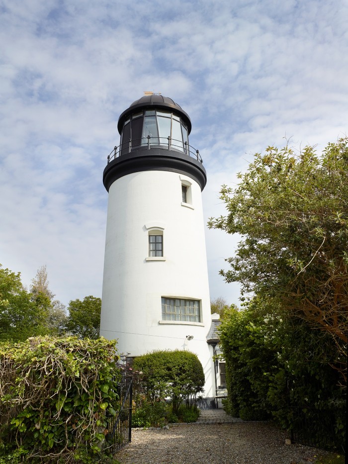 The white-and-black Winterton Lighthouse, flanked by greenery