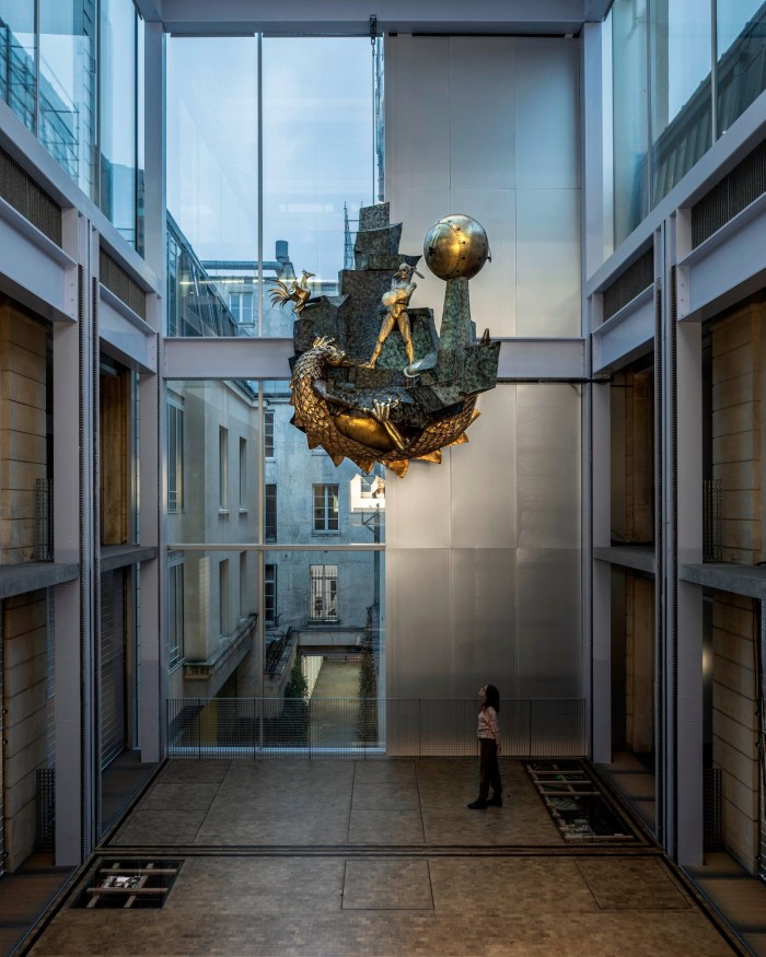 A large sculpture of a man slaying a dragon is hung in an atrium