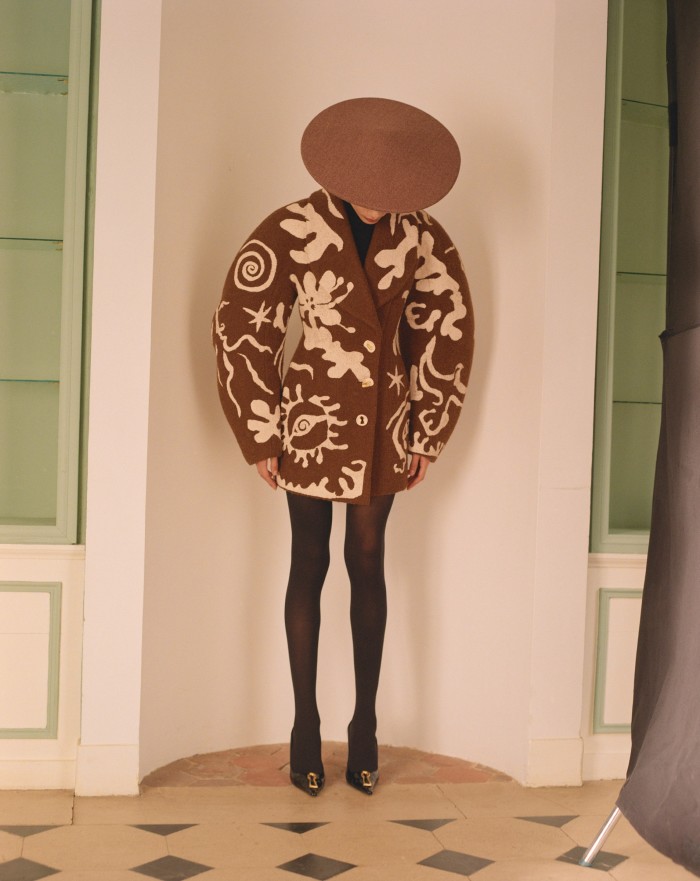 Chaima wears Schiaparelli hand-painte fleece wool-mix coat, €25,000, cashmere Essential rollneck, €2,300, and patent leather pumps, €2,100. Falke sustainable yarn 50 Den tights, £25. Pierre Cardin tweed hat, POA