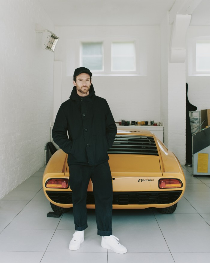 Berryman in his garage with his 1960s Lamborghini Miura P400. He wears Applied Art Forms CM1-1 hooded deck jacket, €790, and cargo trousers, €390